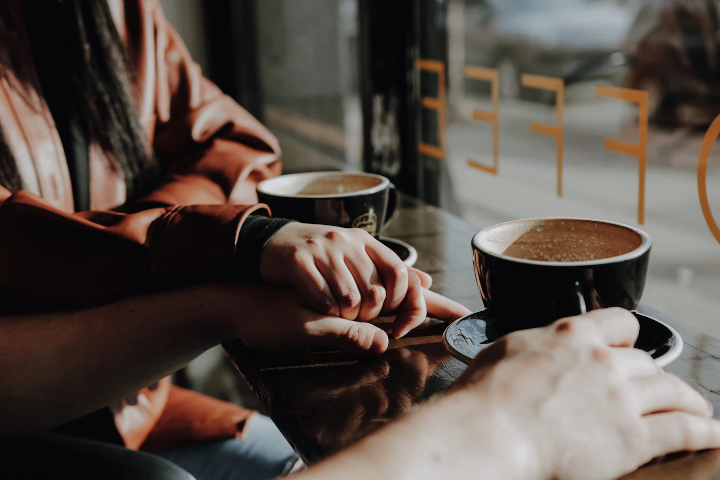 Hands around coffee cups during a conversation at a café table