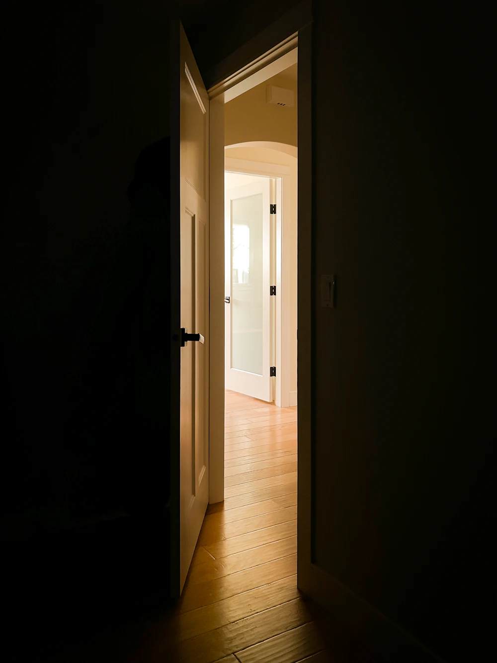 An open door with warm light coming through into a dark room